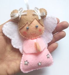 a hand holding a small pink angel ornament