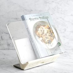 a cookbook is sitting on top of a white plate with a spoon in it