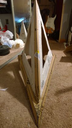 an upside down piece of cardboard sitting on the floor next to a mirror and guitar