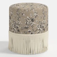 a small stool with fringe trim around the edge and flowers on it's side