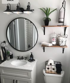 a white toilet sitting under a bathroom mirror next to a sink and shelf filled with items