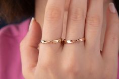 a woman's hand with a gold ring on top of her finger and the other hand holding it up