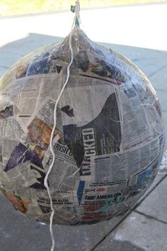 a newspaper ball hanging from a wire on the sidewalk