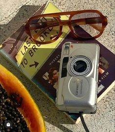 a watermelon and camera sitting on top of a table next to a book