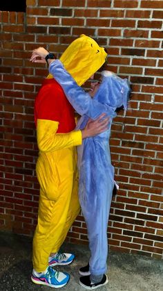 two people dressed as pokemon and winnie the pooh hugging each other in front of a brick wall