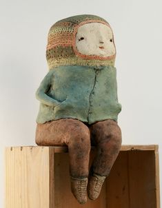 a wooden box with a clay doll sitting on top of it