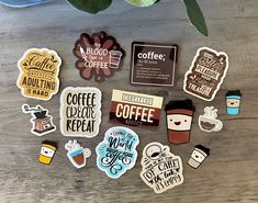 various stickers and decals on a table with a cup of coffee in the background