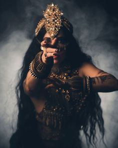 a woman with long black hair and gold jewelry on her face is posing for the camera