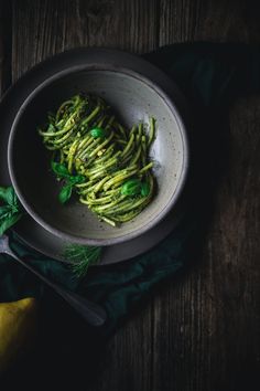 a white bowl filled with green vegetables on top of a table next to a banana