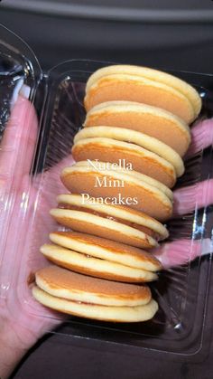 a person holding a plastic container filled with pancakes in it's palm and the words, nutella mini pancakes