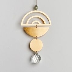 a gold and silver wind chime hanging from a hook on a gray wall next to a beaded ball