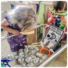 two children are looking at some silver foil