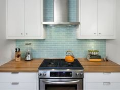 a stove top oven sitting inside of a kitchen next to wooden counter tops and white cabinets