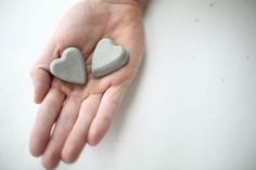 two heart shaped rocks in the palm of someone's hand