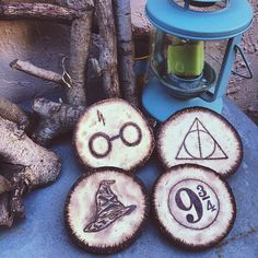 four harry potter coasters sitting on top of a table next to some wood logs