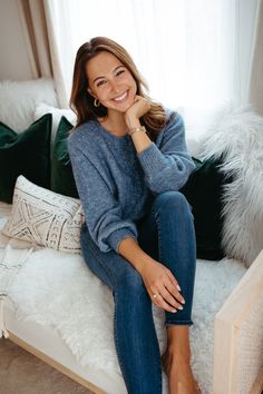 a woman is sitting on a bed with her legs crossed and smiling at the camera