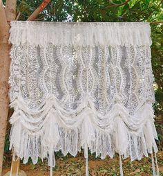 a white lace curtain hanging from a tree