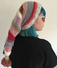 a woman with blue hair wearing a multicolored knitted hat and scarf over her head