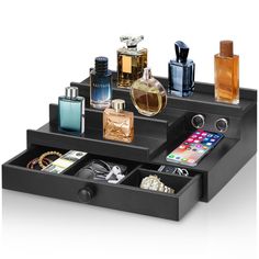 an assortment of perfumes and other items in a black tray on a white background