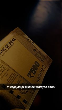 a person holding up a stack of money in front of a dark background with the words bank of india written on it