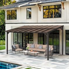 an outdoor living area with couches and tables next to a pool in front of a house