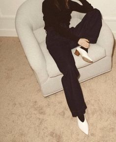 a woman sitting on top of a white chair