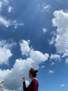 a woman is flying a kite in the blue sky with white clouds above her head