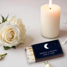 a matchbox with matches and a white rose on it next to a lit candle