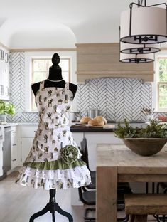 a dress on a mannequin in a kitchen next to a table and chairs