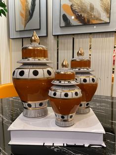 three brown and white vases sitting on top of a table