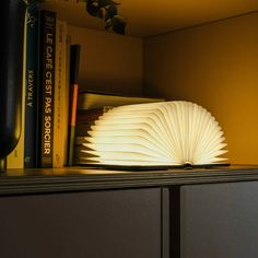 an open book sitting on top of a table next to bookshelves and a lamp