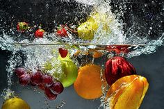 some fruit is falling into the water and being splashed on top of each other