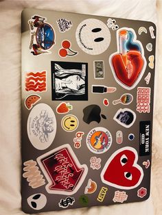 a laptop covered in stickers on top of a bed