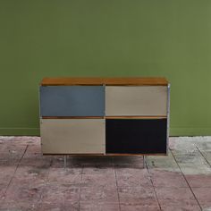 a sideboard with four different colors on it sitting in front of a green wall