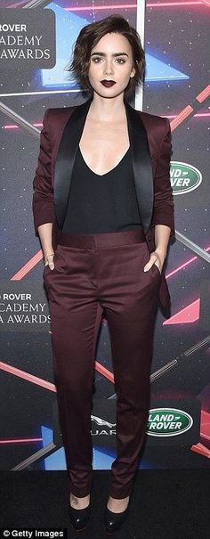 a woman in a black top and maroon pants at an awards event with her hands on her hips