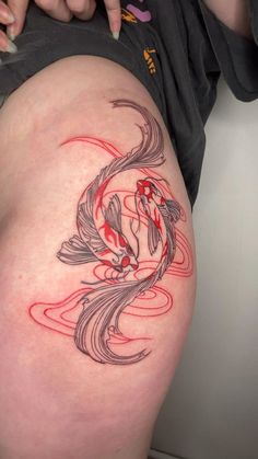 a woman's thigh with a koi fish tattoo on the side and red ink