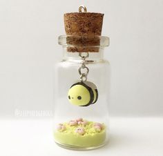 a glass jar with a keychain hanging from it's side filled with tiny flowers