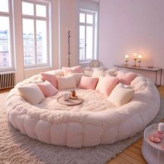 a living room filled with lots of white furniture and pink pillows on top of it