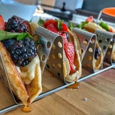 four panini sandwiches with fruit on them are sitting on a wooden counter top, ready to be eaten