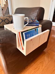 a coffee cup is sitting on top of a magazine rack that holds books and magazines