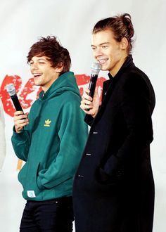 two men standing next to each other holding microphones