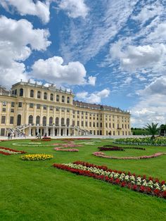 a large building sitting on top of a lush green field next to a flower garden