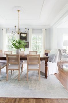 a dining room table with white chairs and a potted plant on top of it