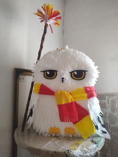 a white stuffed owl sitting on top of a wooden table next to a red and yellow flower