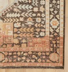 an antique rug with various colors and designs on it, sitting on a wooden floor