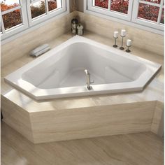 a large white bath tub sitting next to two windows