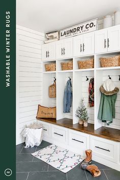 a mud room with white cabinets and lots of coats