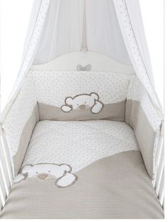 a baby crib with a teddy bear bedding set on it's side