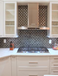 a kitchen with white cabinets and silver backsplashes on the counter top,