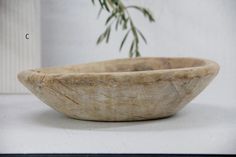 a wooden bowl sitting on top of a white counter next to a potted plant